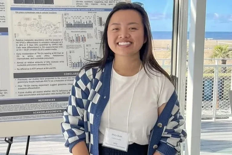 Mary Doan smiling in front of her academic poster