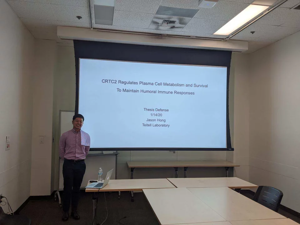 Grad student stands in front of a projected slide, giving his PhD defense