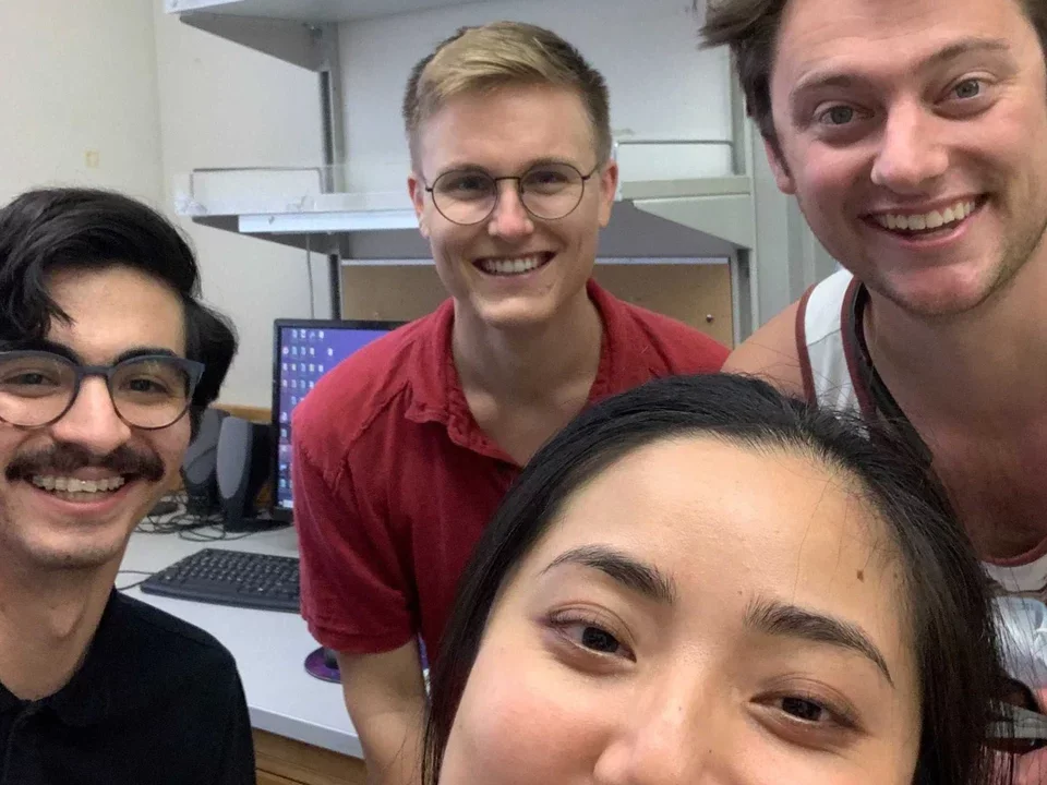 four lab members cluster together for a group selfie in the lab
