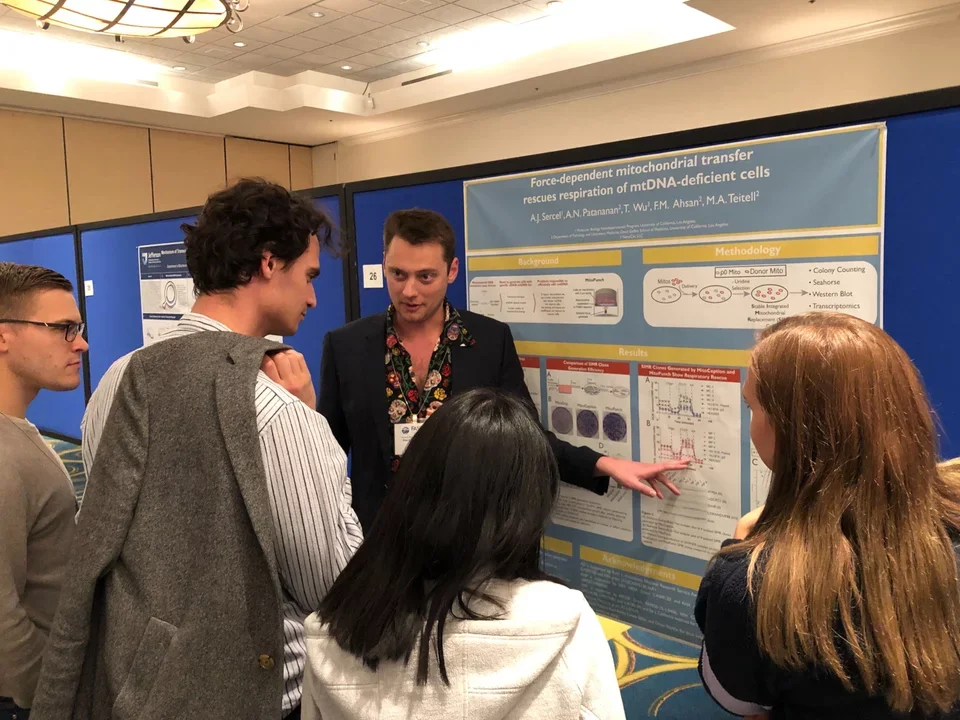 Spectators crowd around a Teitell lab grad student's poster presentation of mitochondrial transfer