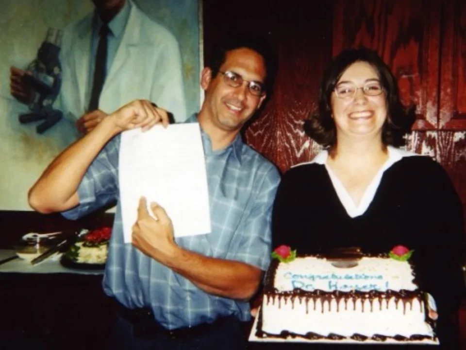 Dr. Teitell stands next to a lab member who just successfully defended her PhD and is holding a cake