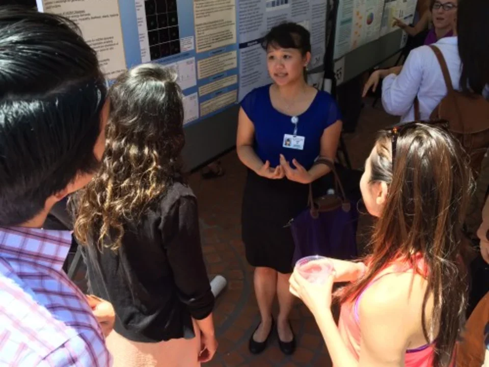 Photo from 2015, a crowd gathers around Tran as she gives her poster presentation