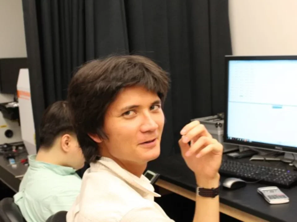 a candid photograph of a postdoc sitting in a lecture hall, turning around to look at the person snapping the photo