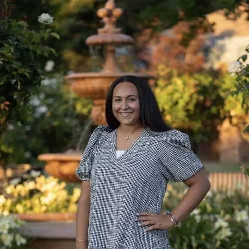 Julianna Youssef stands smiling in front of a beautiful fountain