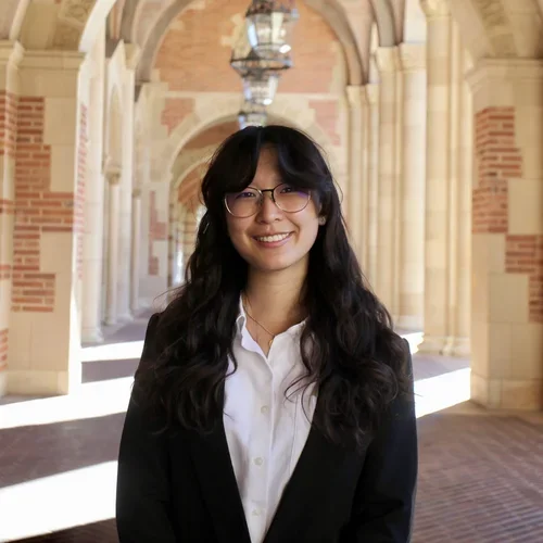A student smiles at the camera in front of a deep architectural structure