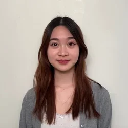 Annie Pham smiling standing with her back to a white wall