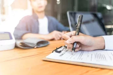 Someone writes notes on document on a clipboard.